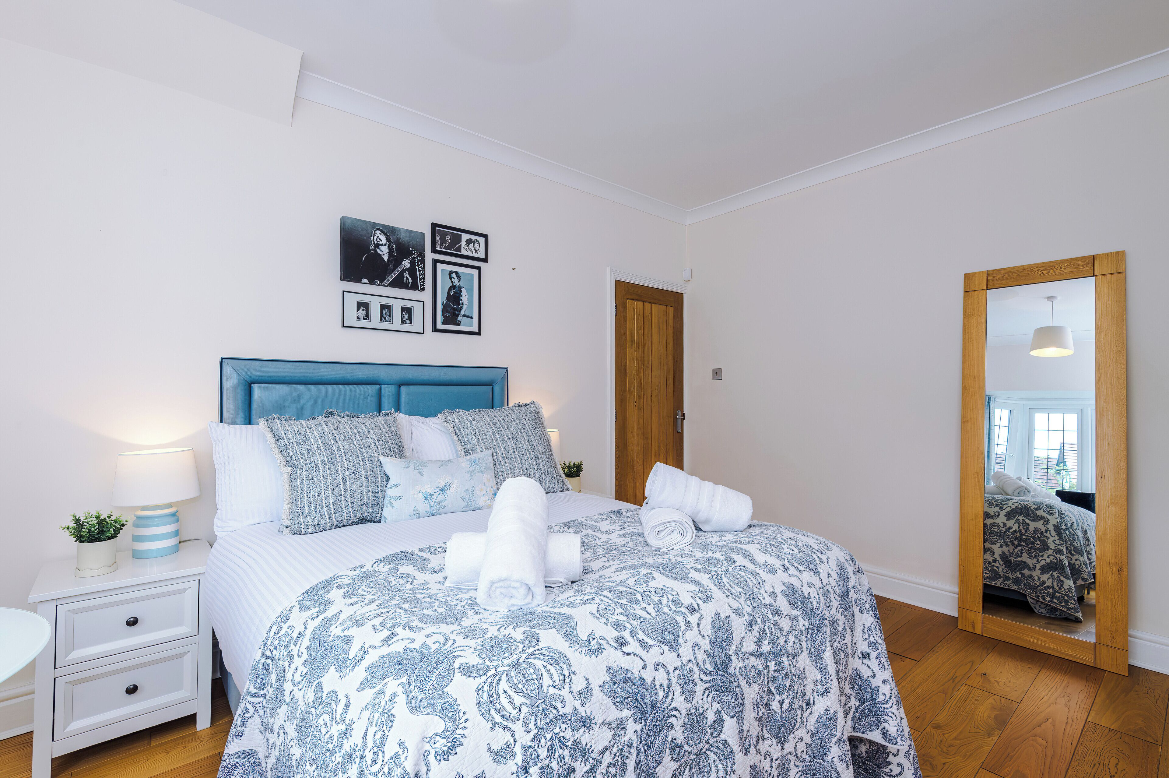 Une chambre à coucher avec un lit, des tables de chevet, un miroir et des tableaux encadrés accrochés au mur.