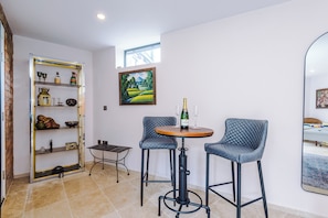A room with a dining table, two chairs, a bookshelf, and a painting on the wall. - *NEW* Funky 4BR Home | Sleeps 8 | Driveway | PS4 (Greater Manchester)