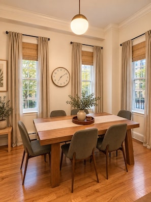 A dining room with a wooden table, six chairs, a clock on the wall, and a hanging light fixture. - Huge NYC Townhouse Near High Line & Meatpacking (New York)