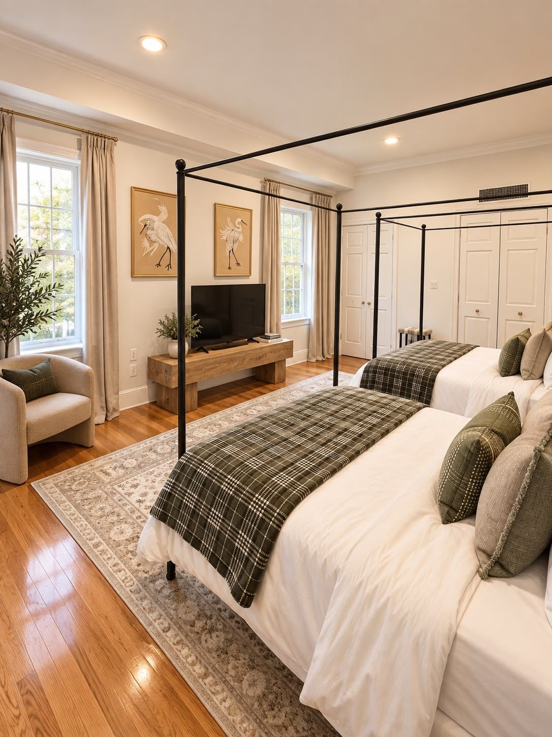A bedroom with a four-poster bed, a TV on a wooden stand, and a large window with curtains.