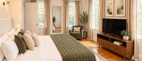 A spacious bedroom with a large bed, a television, and a seating area.