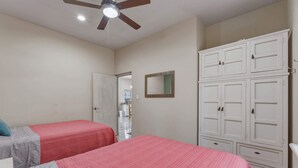Ein Schlafzimmer mit zwei Betten, einem Deckenventilator und einem Kleiderschrank.