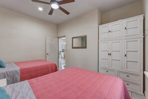 Ein Schlafzimmer mit zwei Betten, einem Deckenventilator und einem Kleiderschrank.