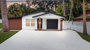 Ein Wohnhaus mit Garage, Auffahrt und weißem Zaun.