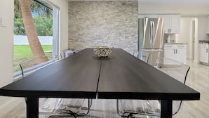 Eine moderne Küche mit Steinrückwand, Edelstahlgeräten und einem Essbereich mit einem langen Tisch und Stühlen.