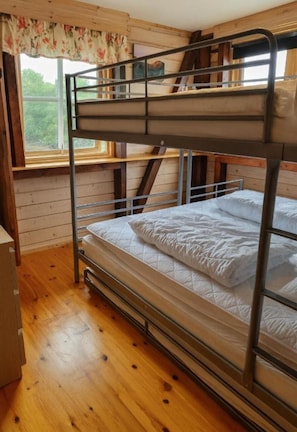 Ein Schlafsaal mit Etagenbetten, Holzwänden und einem Fenster.