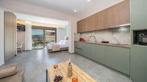 Una cuina moderna amb forn integrat, zona de menjador amb taula i cadires, i dormitori amb llit i balcó.
