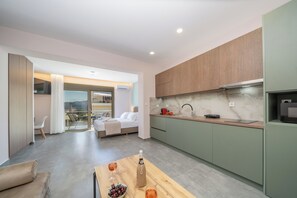 Eine moderne Küche mit Einbauofen, ein Essbereich mit Tisch und Stühlen sowie ein Schlafzimmer mit Bett und Balkon.