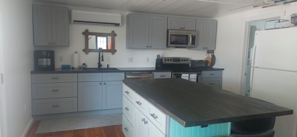 A kitchen with grey cabinets, a microwave, a coffee maker, and a sink. - Relaxing Willsboro Waterfront Cottage (Willsboro)