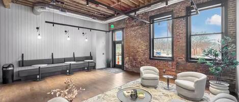 A modern lounge area with seating, a coffee table, and a view through a large window.