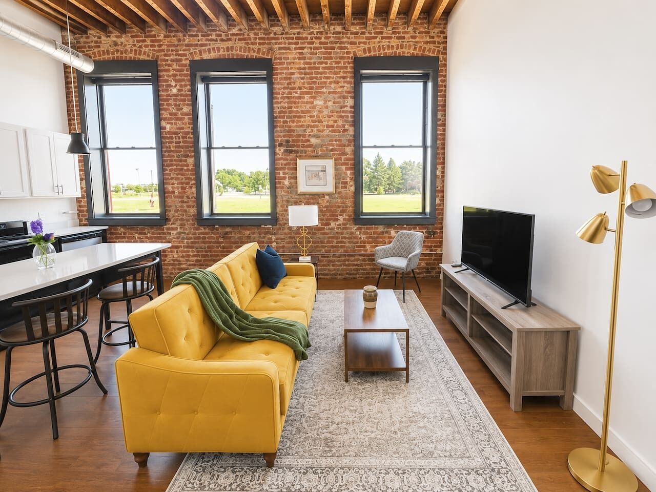 A living room with a yellow sofa, a television, and a brick wall.