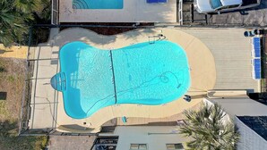 An aerial view of a swimming pool with a deck, surrounded by a fence and palm trees. - Sun-kissed Dunes: 2-bedroom condo Oceanfront; pool sleeps 6 (Myrtle Beach)