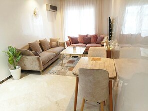 Ein Wohnzimmer mit Sofa, Couchtisch und Esstisch mit Stühlen.