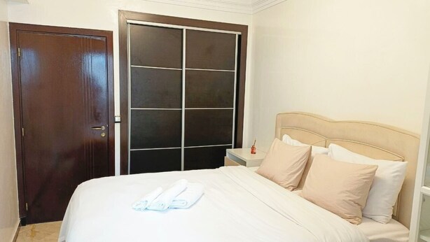 Una camera d'albergo con un letto, un comodino, una porta in legno e una porta scorrevole in vetro.