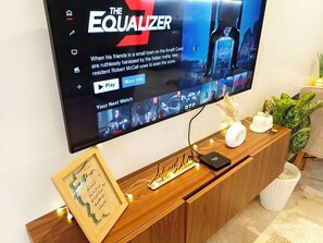 Ein Flachbildfernseher an einem Holzkasten, versehen mit einem Bilderrahmen und dekorativen Gegenständen.
