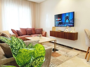 Ein Wohnzimmer mit Sofa, Couchtisch und einem an der Wand befestigten Fernseher, der eine Fernsehsendung zeigt.