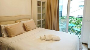 Una camera d'albergo con un letto, un armadio e un balcone con mobili da esterno.