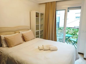Ein Hotelzimmer mit einem Bett, einem Kleiderschrank und einem Balkon mit Gartenmöbeln.