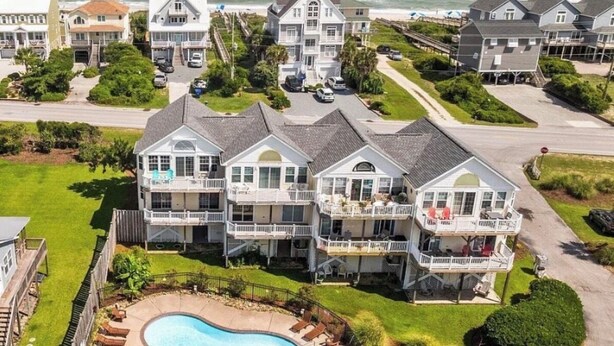 A multi-story residential building with a pool, surrounded by greenery and a view of the ocean. - High Tides & Pink Skies-3BR, Pool, Views, Linens, Steps to Beach - North Topsail (North Topsail Beach)