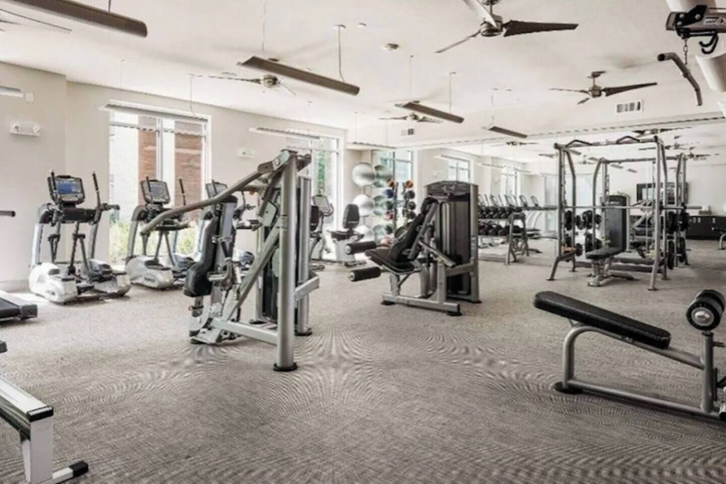 Une salle de sport équipée de divers appareils d’exercice, notamment des tapis de course, des appareils de musculation et des poids libres.