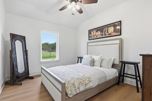 Ein Schlafzimmer mit einem Bett, einem Fenster, einem Deckenventilator und einem Gemälde an der Wand.