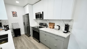 A modern kitchen with stainless steel appliances, a marble countertop, and grey cabinetry. - 3BR Hollywood Home nr Hard Rock, Beach & FLL (Hollywood)