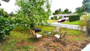 A backyard with a patio table and chairs, a lawn, and a house in the background. - 3BR Hollywood Home nr Hard Rock, Beach & FLL (Hollywood)