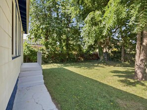 A residential property with a front yard, a staircase leading to a door, and a tree-lined background. - Charming Del Ray Home, Near Old Town & METRO-rail (Alexandria)
