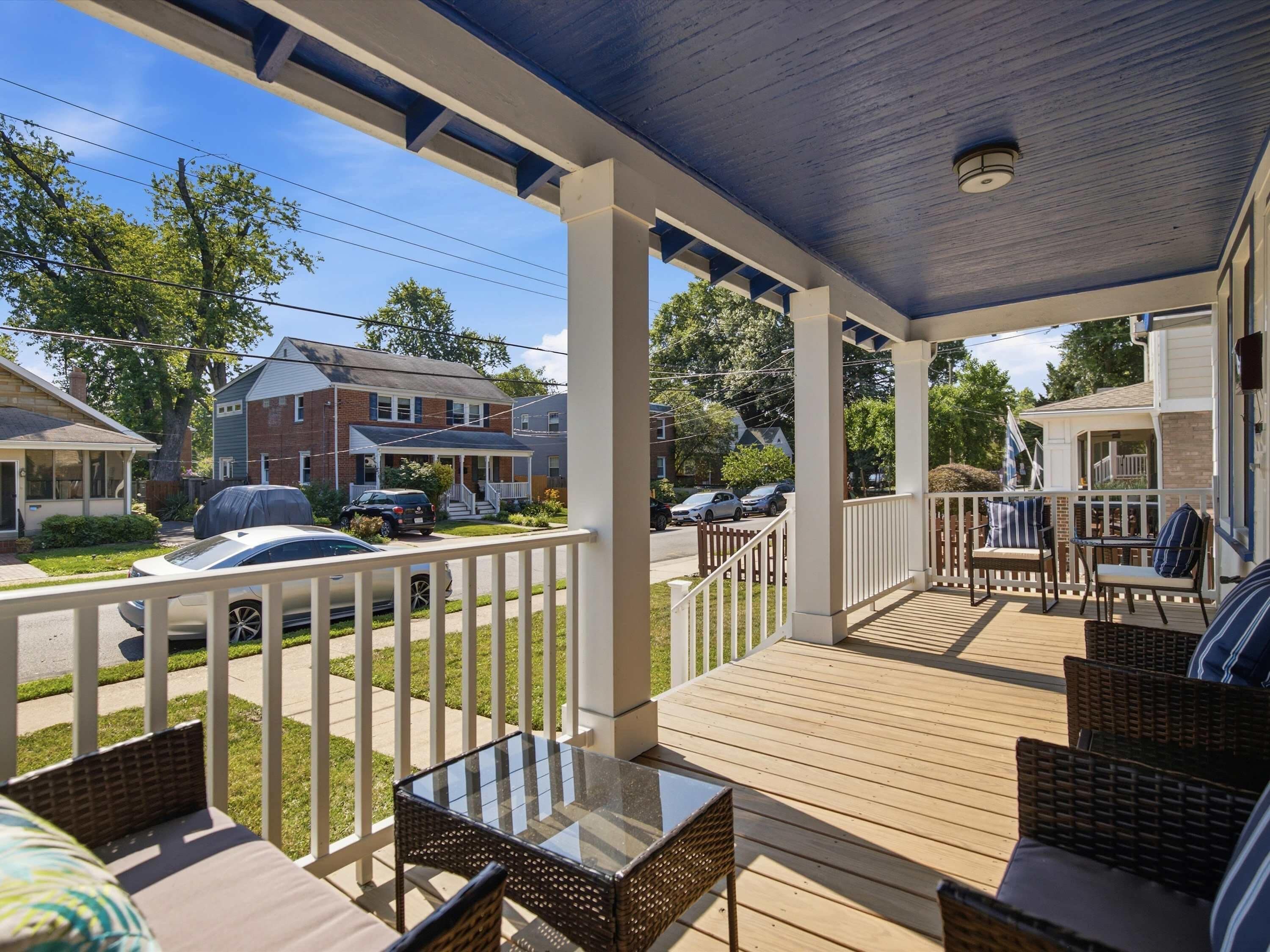 Un porche cubierto con muebles de exterior y vistas a casas residenciales.