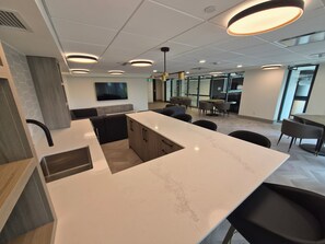 A modern kitchen with a marble countertop, black chairs, and pendant lighting. - Aqua Oasis Beach Club Resort 2.0 - Located right on the beach. (Kelowna)