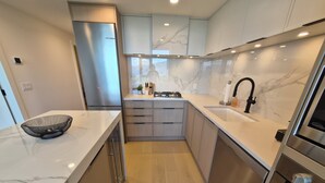 Eine moderne Küche mit Marmorarbeitsplatten, Edelstahlgeräten und Holzschränken.