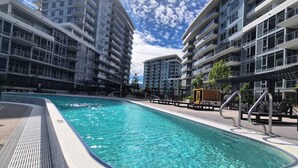 Ein Swimmingpool, umgeben von modernen Apartmentgebäuden mit Balkonen.