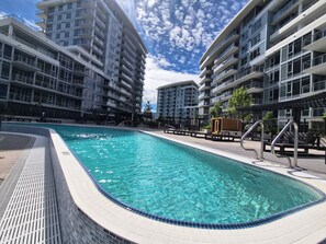 A swimming pool surrounded by modern apartment buildings with balconies. - Aqua Oasis Beach Club Resort 2.0 - Located right on the beach. (Kelowna)