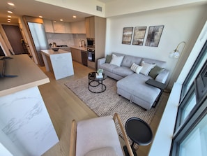Ein modernes Wohnzimmer mit Sofa, Couchtisch und einem Essbereich mit Tisch und Stühlen.