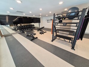 A gym with exercise equipment, a wall-mounted TV, and a motivational poster. - Aqua Oasis Beach Club Resort 2.0 - Located right on the beach. (Kelowna)