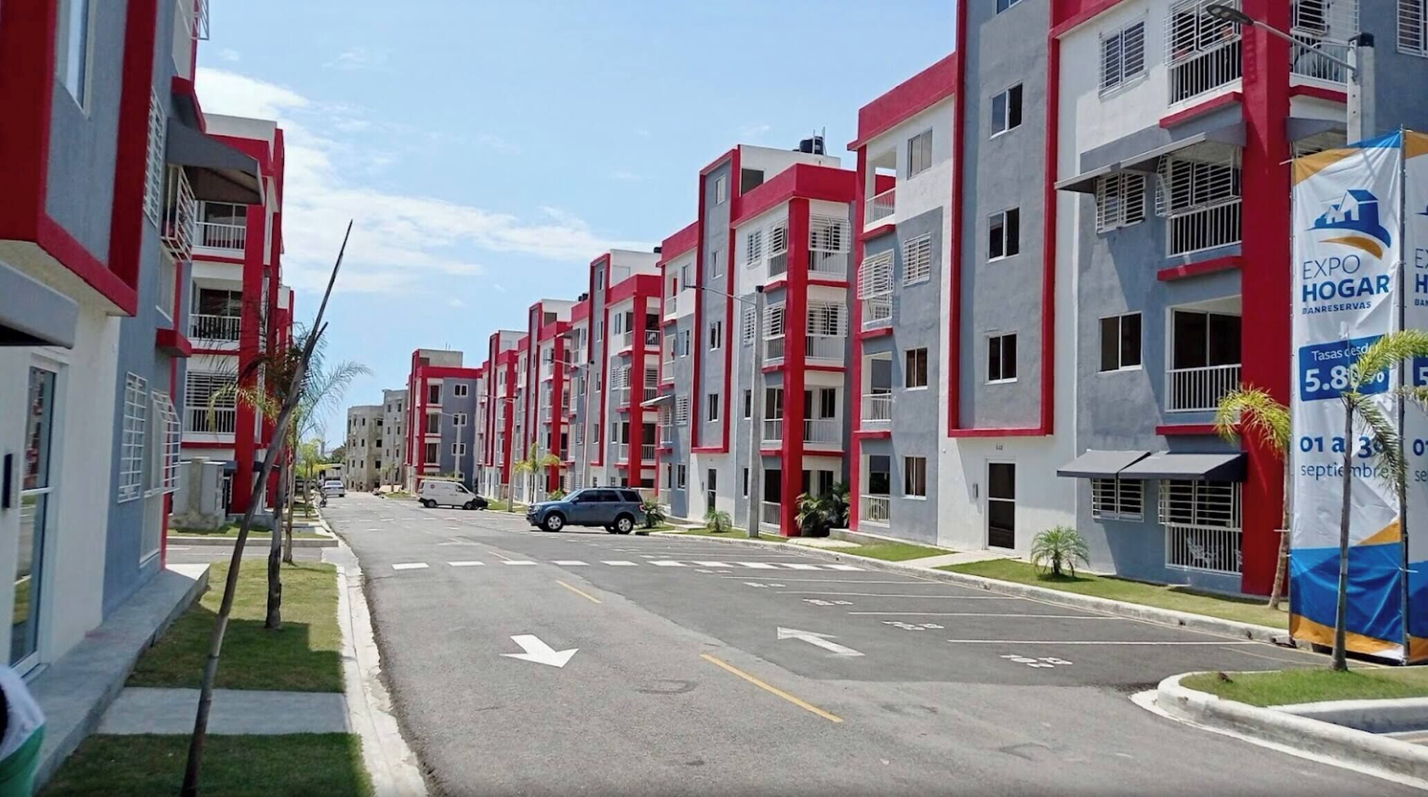 Eine Reihe moderner Wohngebäude mit Balkonen, ein klarer Himmel und eine Straße mit Autos.