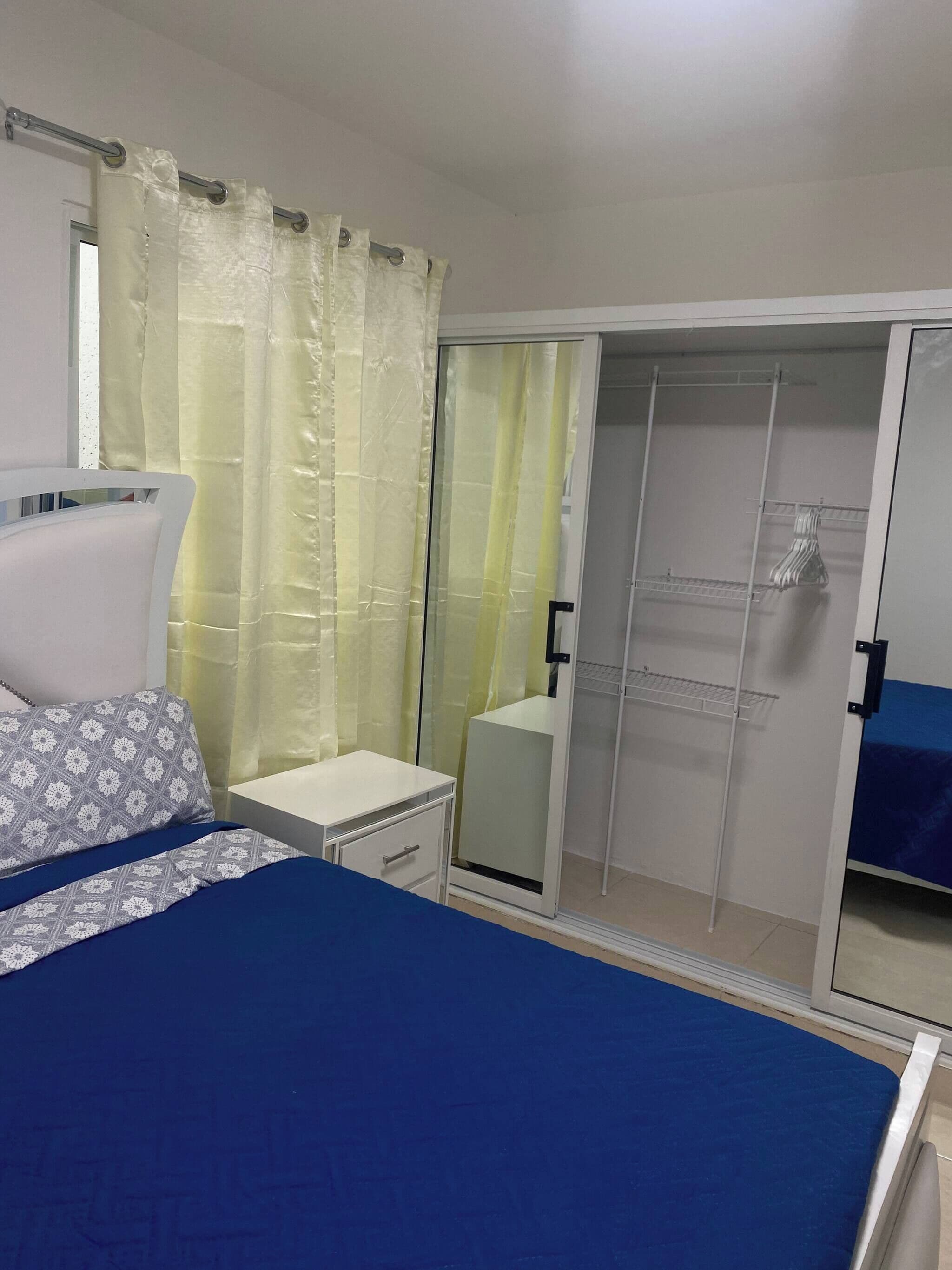Un dormitorio con cama, mesita de noche, armario y zona de ducha.