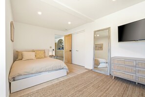 A bedroom with a bed, a dresser, a TV, and a mirror. - Coastal Sanctuary: Newly Remodeled, Unrivaled Views, Sauna, and Steps to Ferry! (Sausalito)