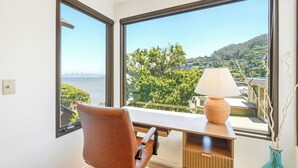 A room with a desk, chair, and a view of a body of water and greenery. - Coastal Sanctuary: Newly Remodeled, Unrivaled Views, Sauna, and Steps to Ferry! (Sausalito)