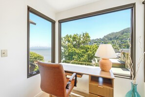 A room with a desk, chair, and a view of a body of water and greenery. - Coastal Sanctuary: Newly Remodeled, Unrivaled Views, Sauna, and Steps to Ferry! (Sausalito)