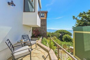 A balcony with a table and chairs, a small garden, and a view of the sea. - Coastal Sanctuary: Newly Remodeled, Unrivaled Views, Sauna, and Steps to Ferry! (Sausalito)