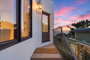A modern building with a balcony, a welcome mat, and a view of the sunset. - Coastal Sanctuary: Newly Remodeled, Unrivaled Views, Sauna, and Steps to Ferry! (Sausalito)