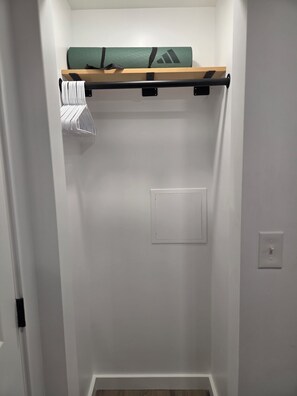 A walk-in closet with a wooden shelf, a hanging rack, and a light switch on the wall. - Centrally located 1-bedroom apartment close to downtown Wifi AC washer/dryer (Twin Falls)