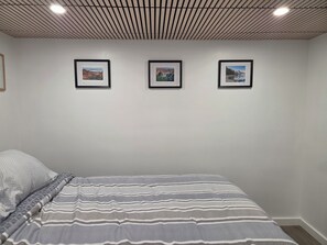 A bedroom with a bed, a wall-mounted picture, and a ceiling with a grid pattern. - Centrally located 1-bedroom apartment close to downtown Wifi AC washer/dryer (Twin Falls)
