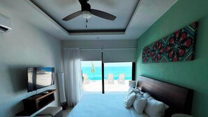 Ein Hotelzimmer mit Bett, Fernseher, Deckenventilator und Meerblick.
