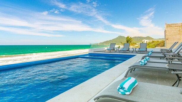 Ein Poolbereich mit Liegestühlen und Blick auf den Ozean.