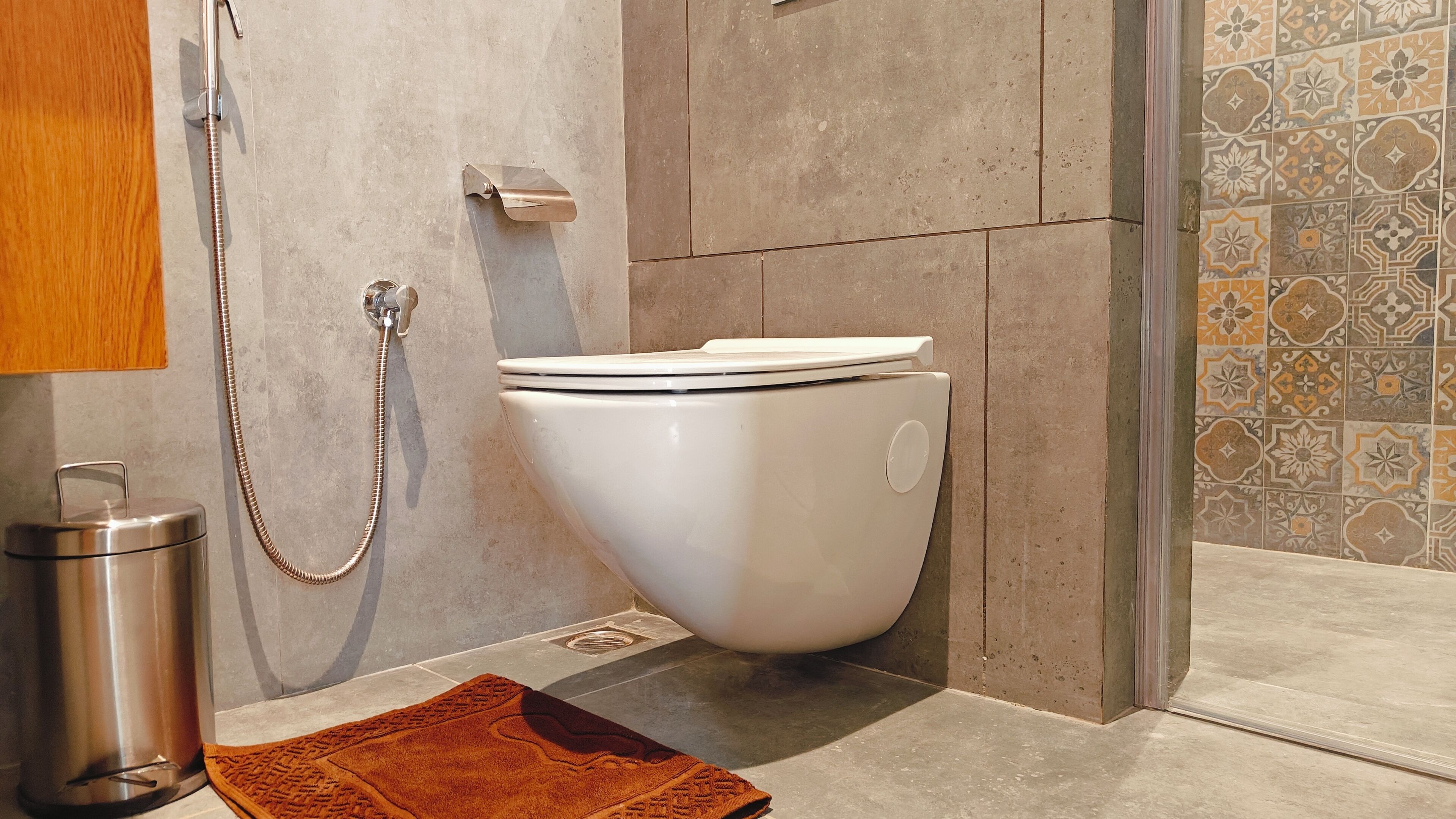 Ein modernes Badezimmer mit Toilette, Dusche und einem Metall-Mülleimer.