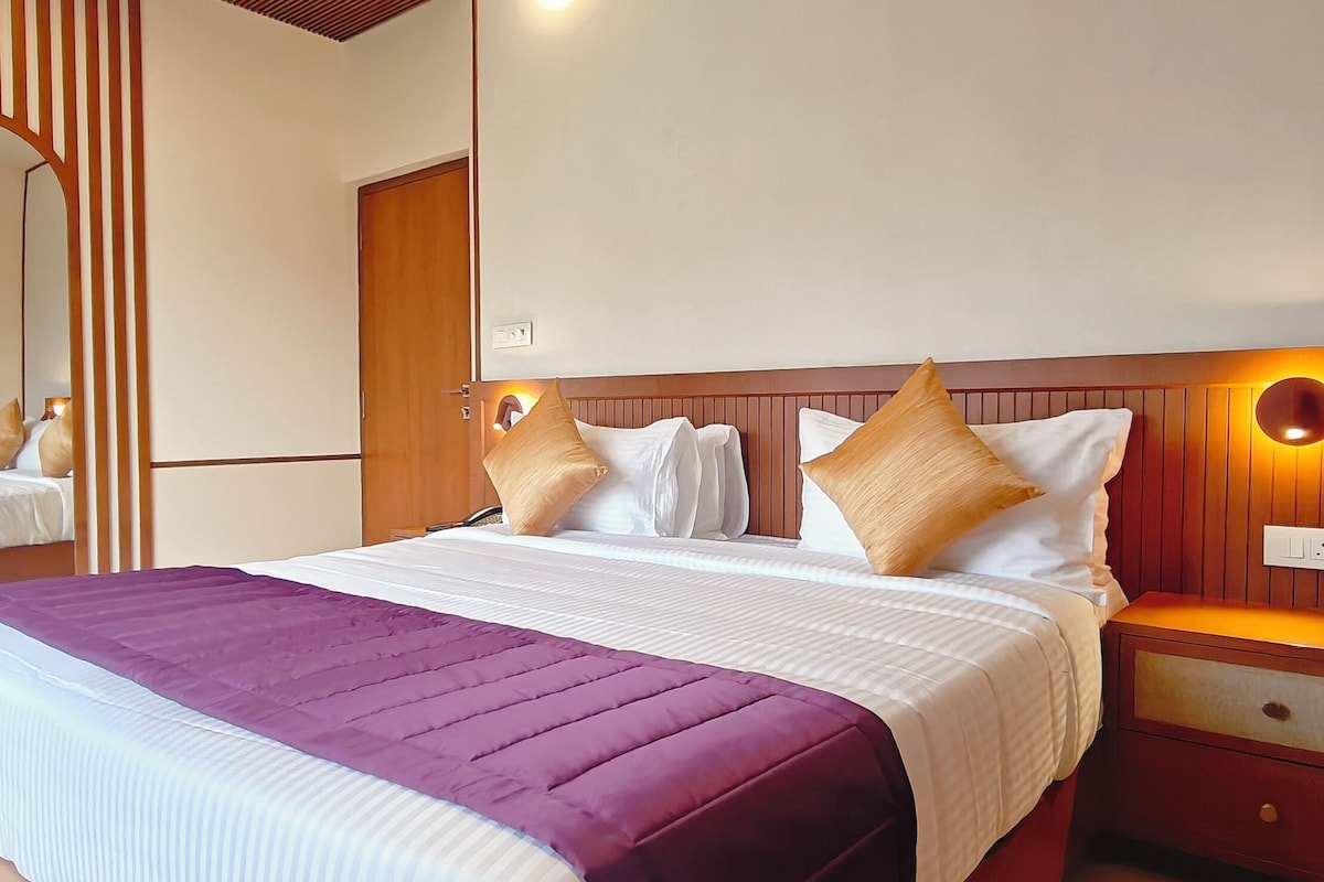 Una camera d'albergo con un letto grande, un comodino, uno specchio e una lampada a parete.
