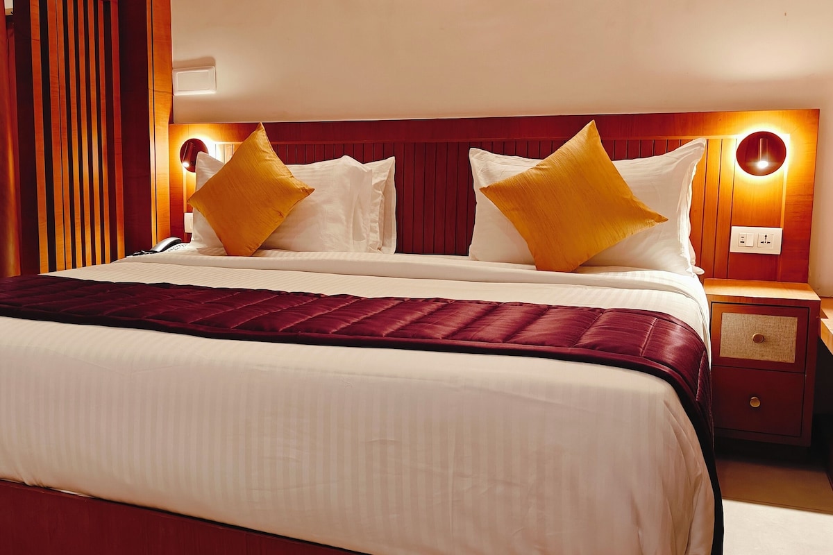 Una camera d'albergo con un letto grande, un comodino e una lampada a parete.