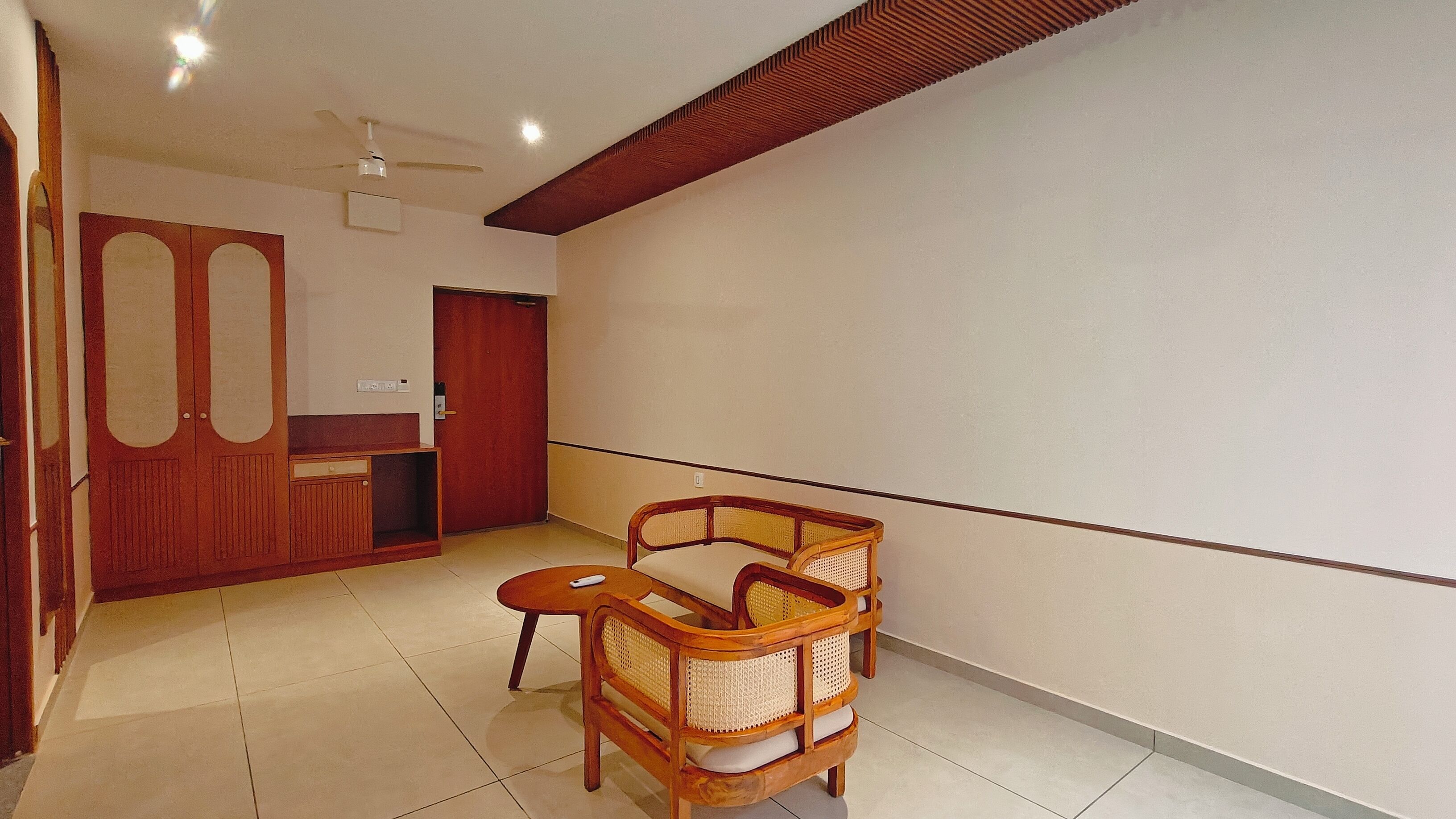 A room with a wooden reception desk, a door, a ceiling fan, and a rattan chair.